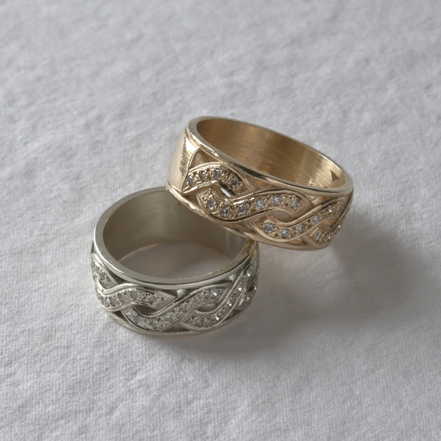 Celtic style gold and diamond eternity rings, stacked together. \pictured on white.
