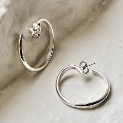 Sterling silver curved hoops, photographed on Cotswold stone. Handmade fine jewellery by Madeleine.