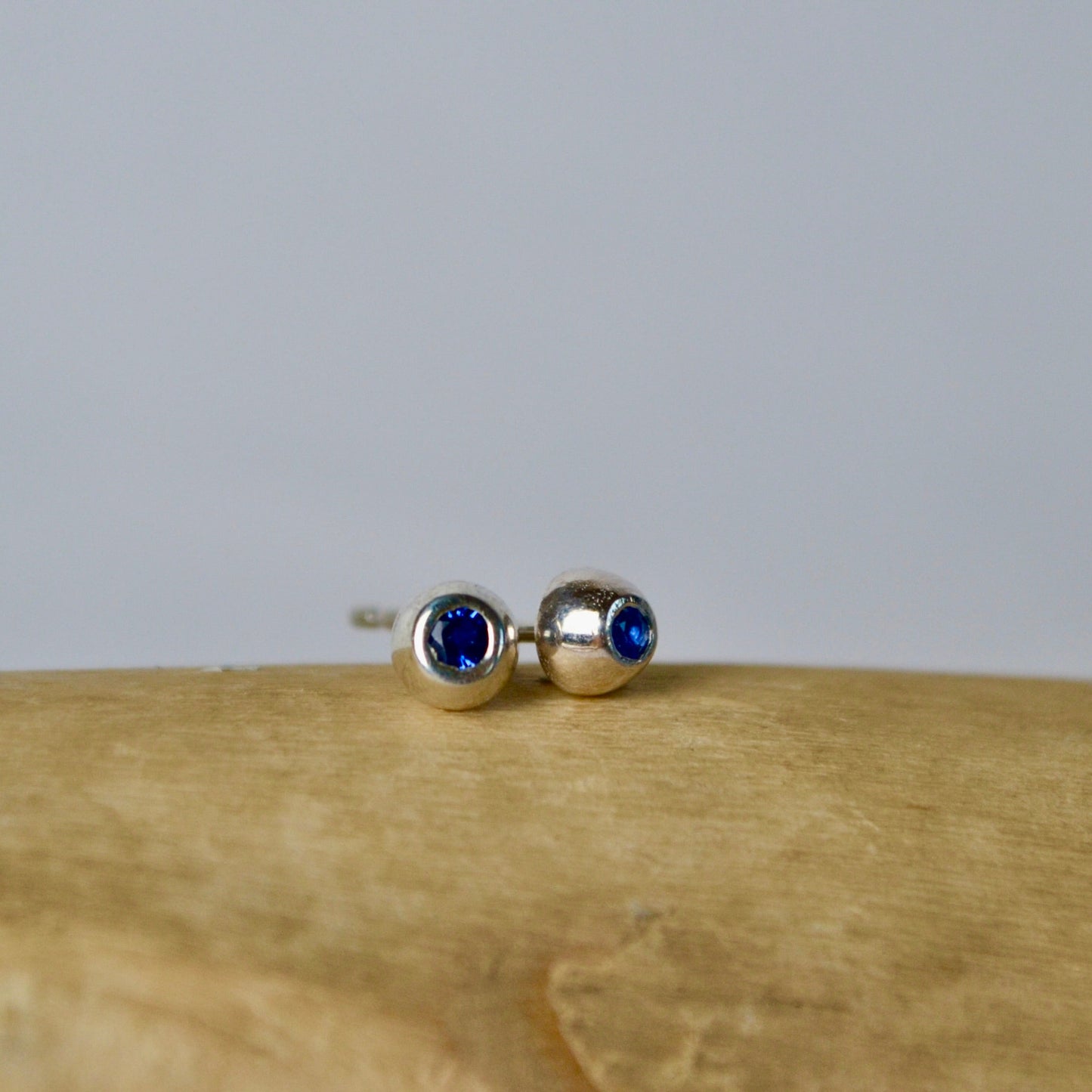 Pair of silver earrings with blue gemstones on a wooden surface.