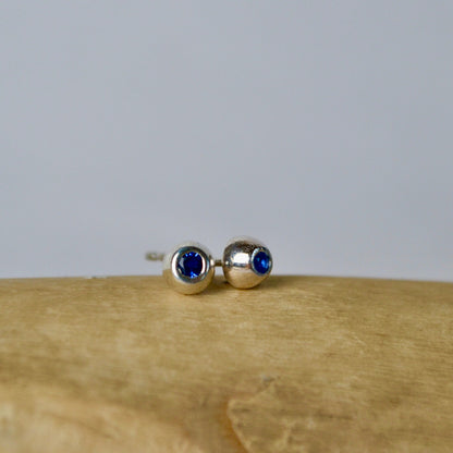 Pair of silver earrings with blue gemstones on a wooden surface.
