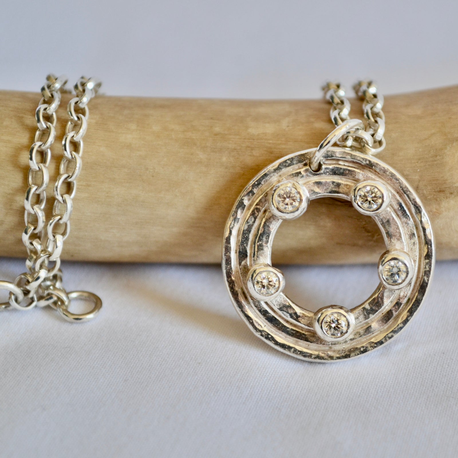 Silver necklace with a circular pendant on a light gray background
