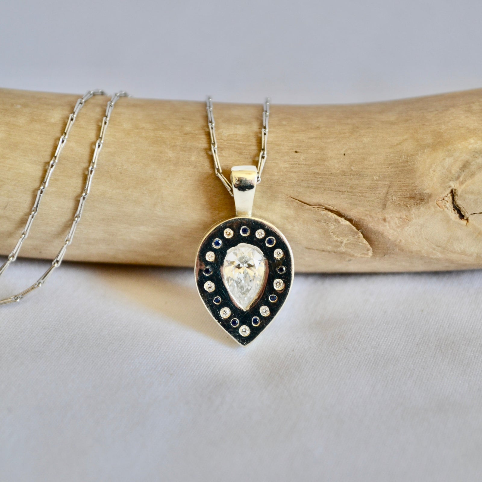 Necklace with a heart-shaped pendant on a piece of driftwood