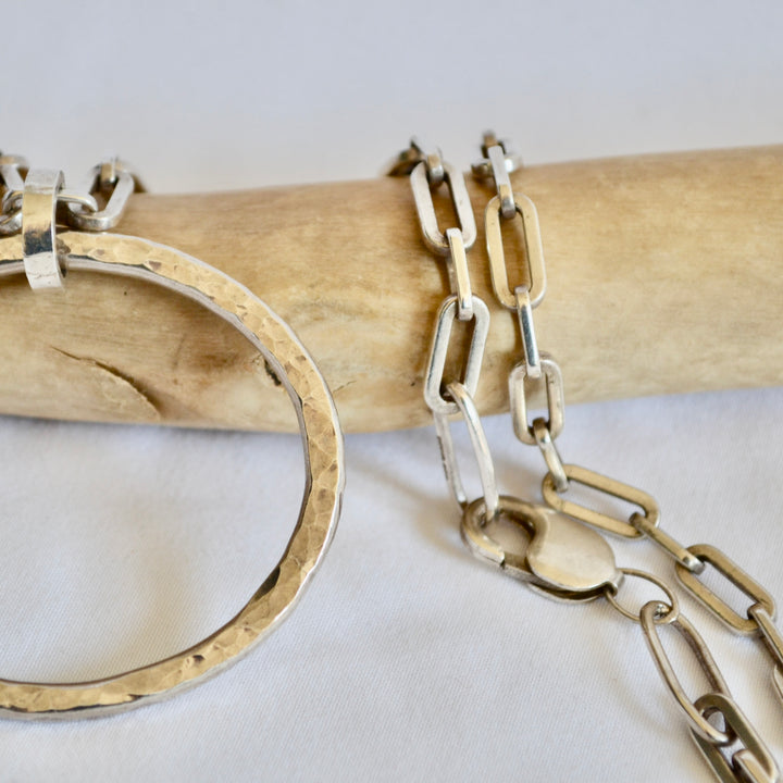 Two silver bracelets on a wooden stick with a white background