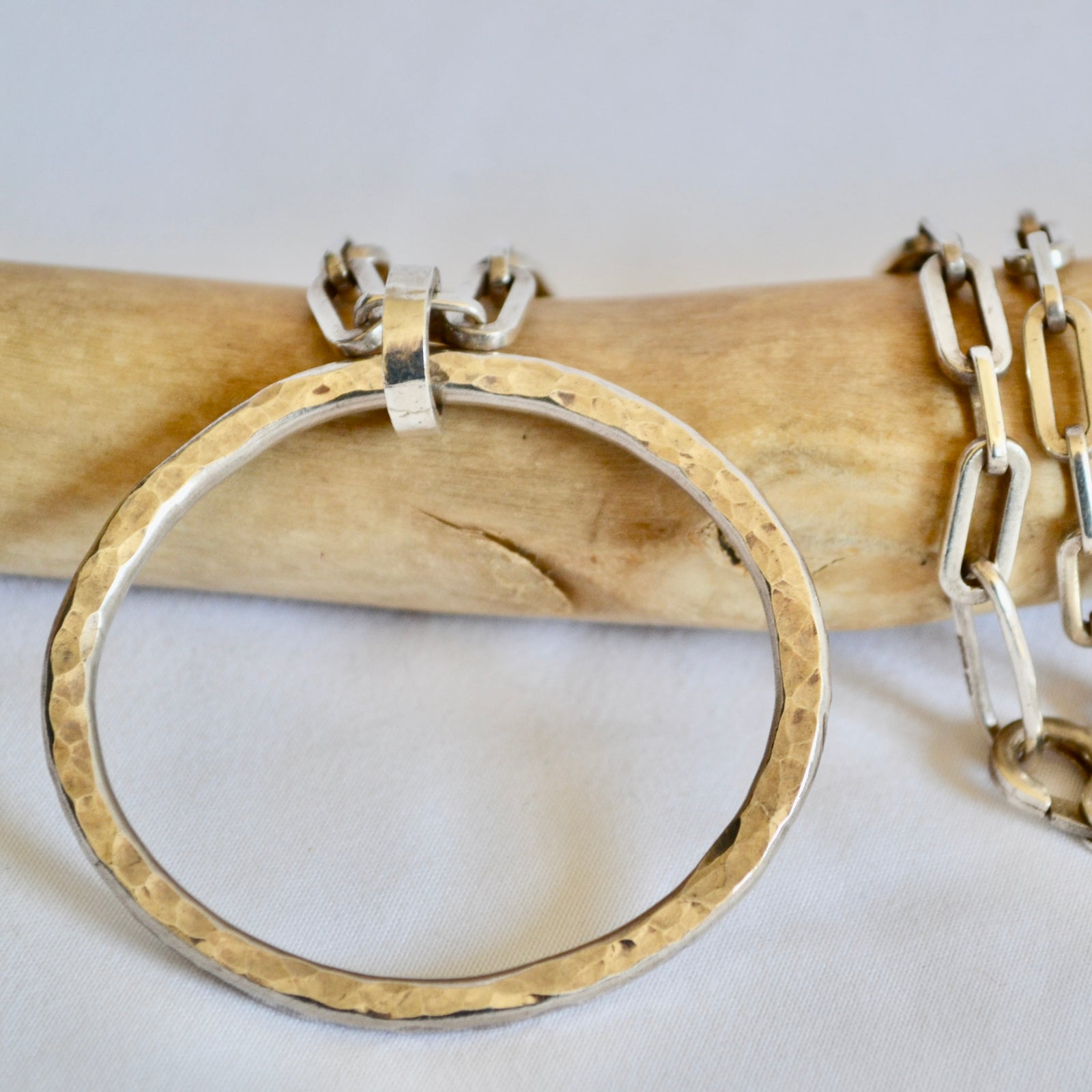 Gold hoop earring on a wooden stick with a white background