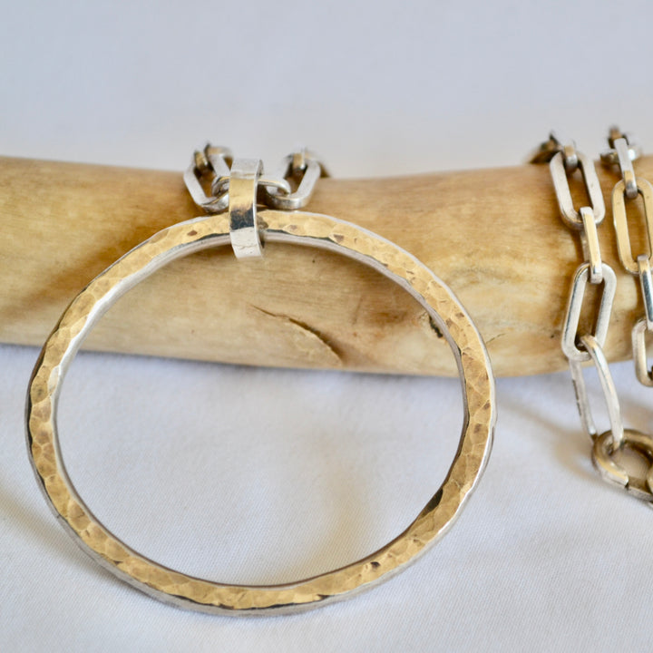 Gold hoop earring on a wooden stick with a white background
