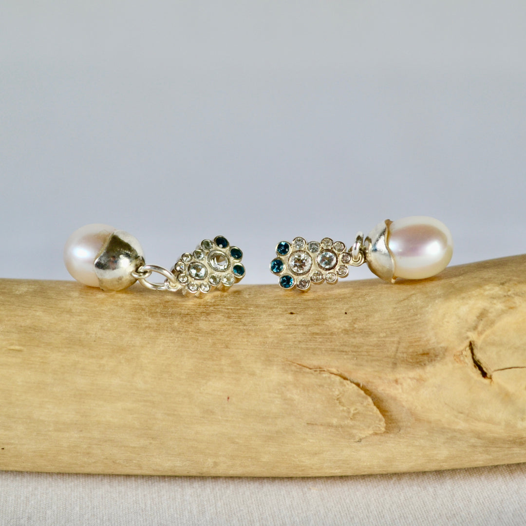 Pair of pearl earrings with gemstones on a wooden surface