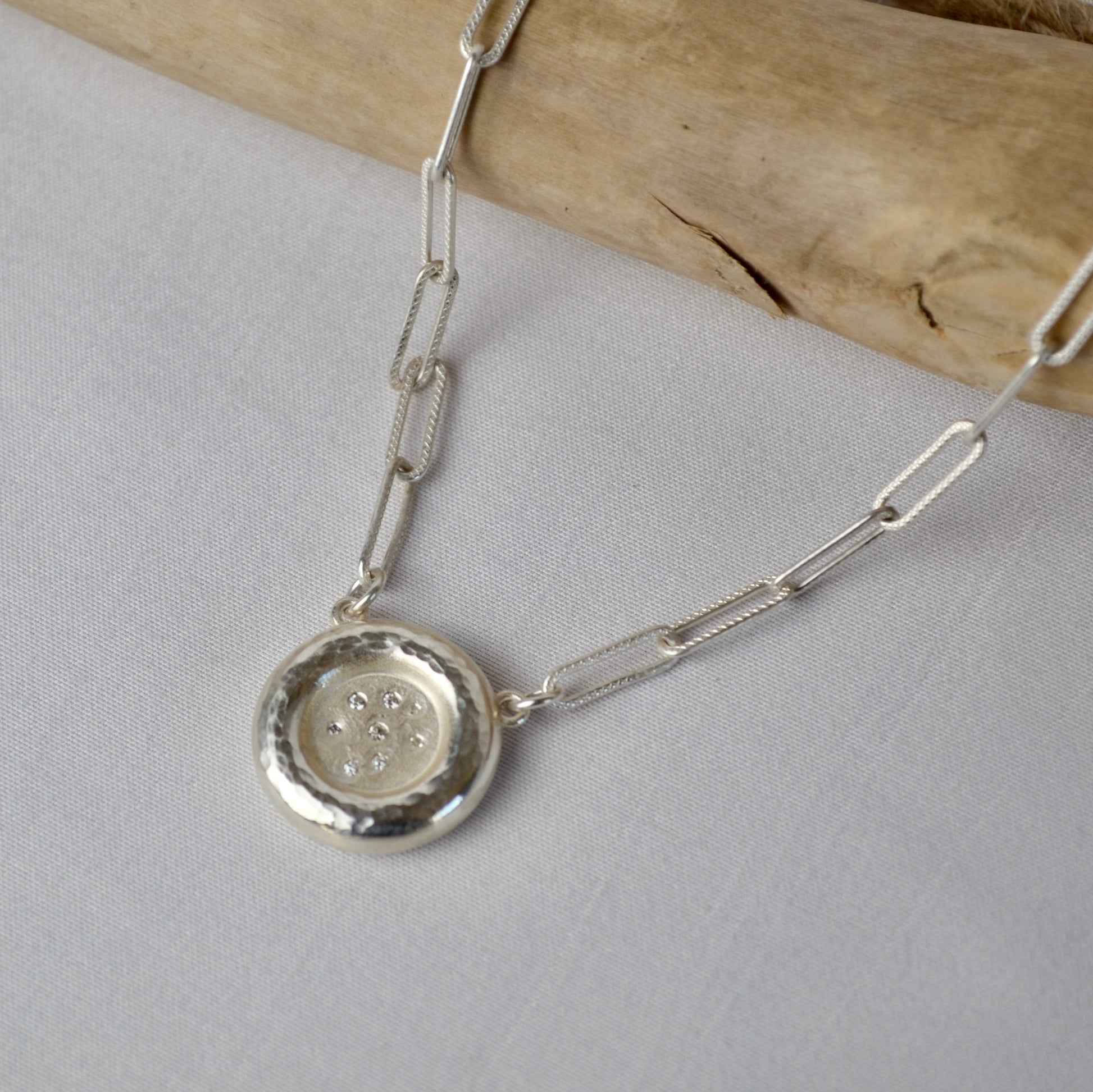 Silver necklace with a round pendant on a light gray background