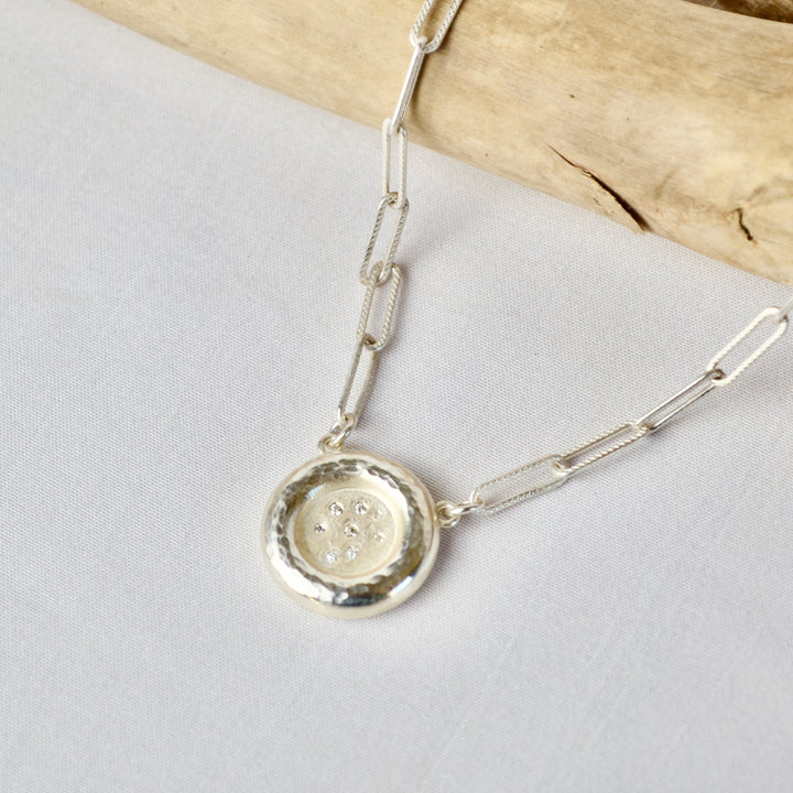 Silver necklace with a round pendant on a light gray background