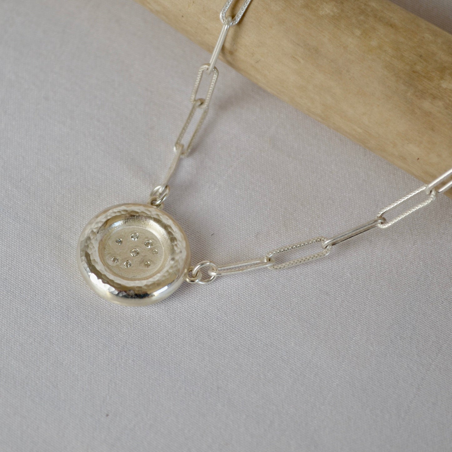 Silver necklace with a round pendant on a light gray background