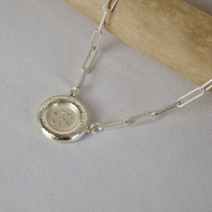 Silver necklace with a round pendant on a light gray background