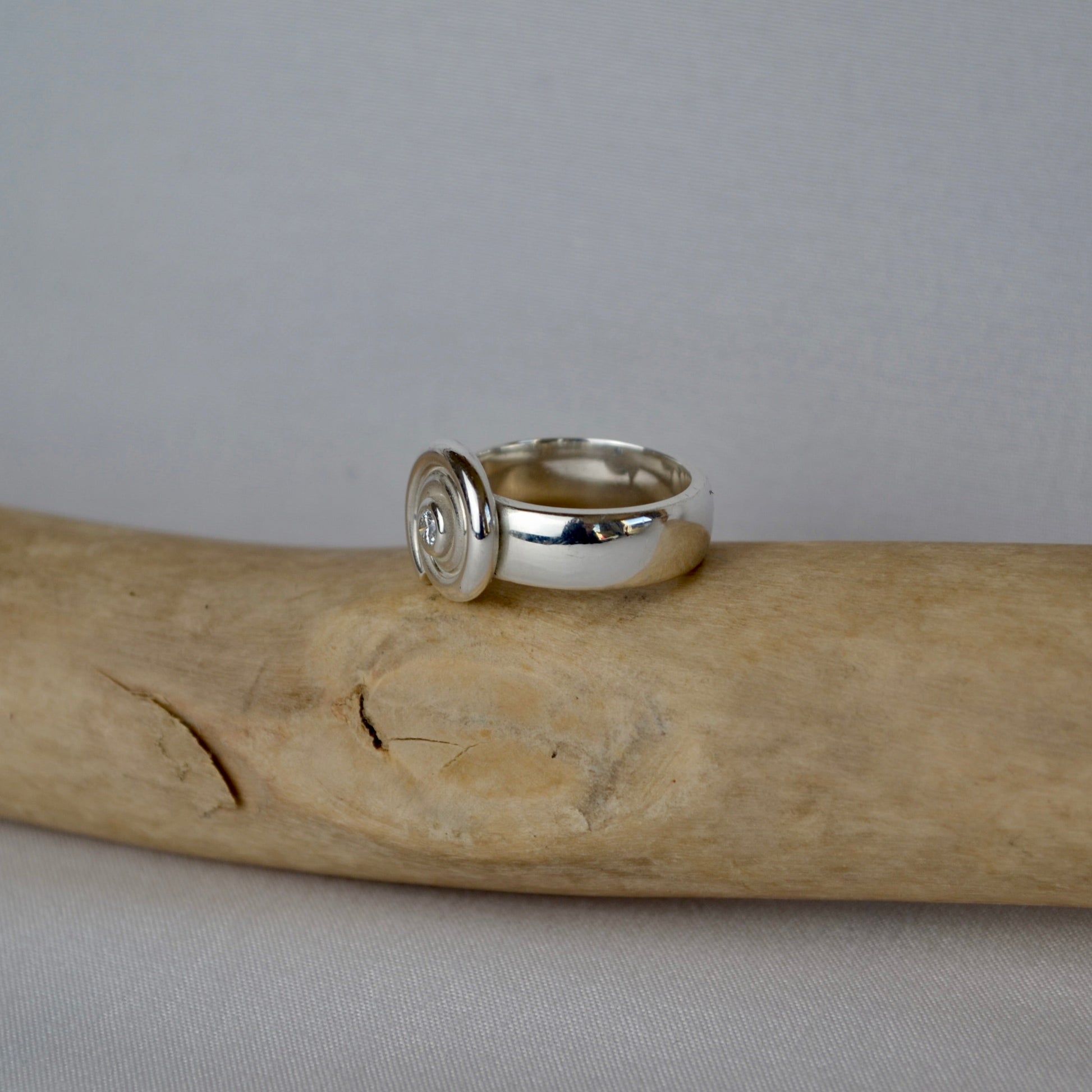 Silver ring on a piece of driftwood with a plain background