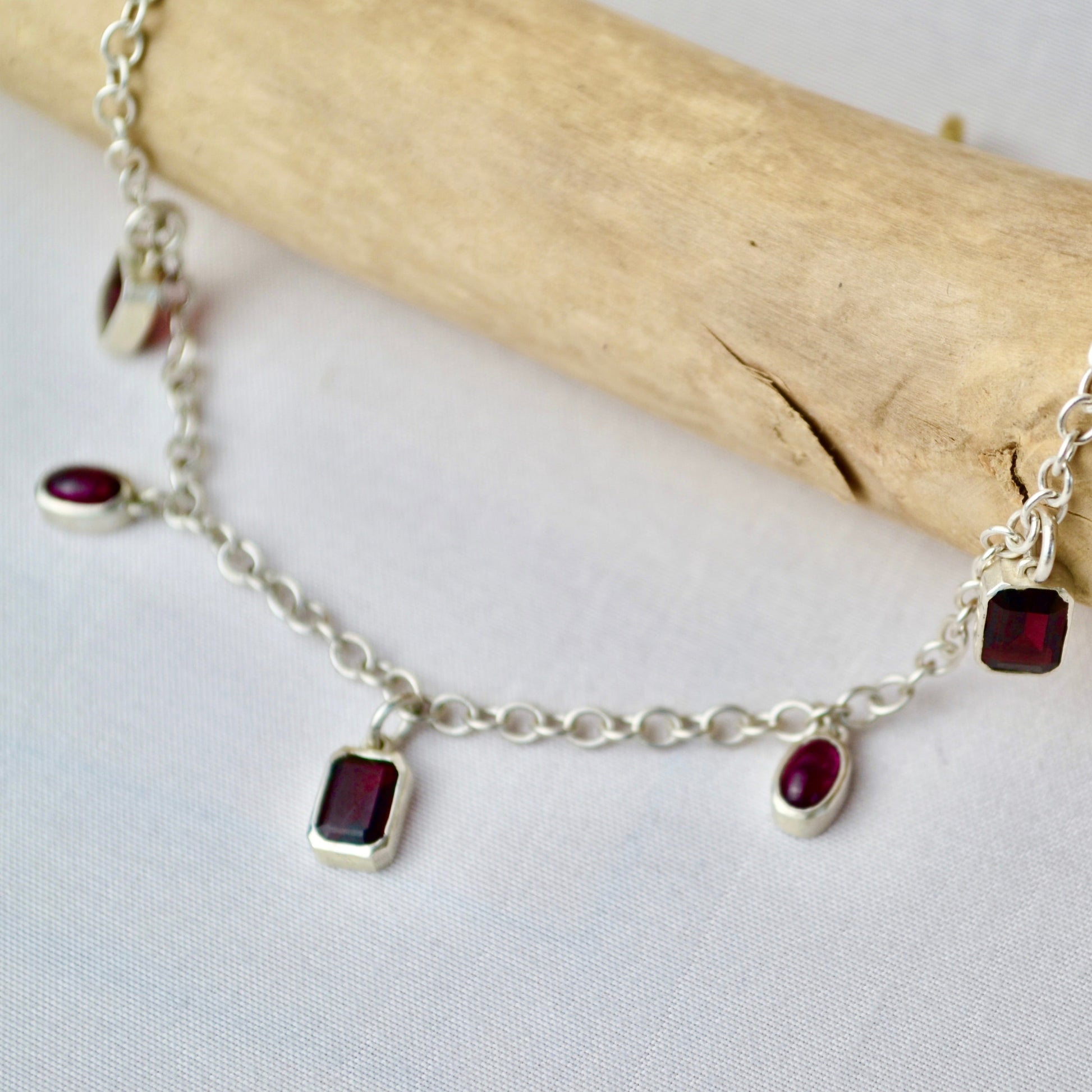 Silver bracelet with red gemstones on a white background