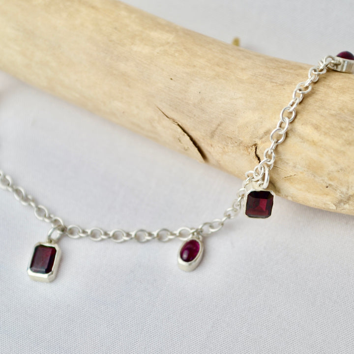 Silver bracelet with red gemstones on a light gray background
