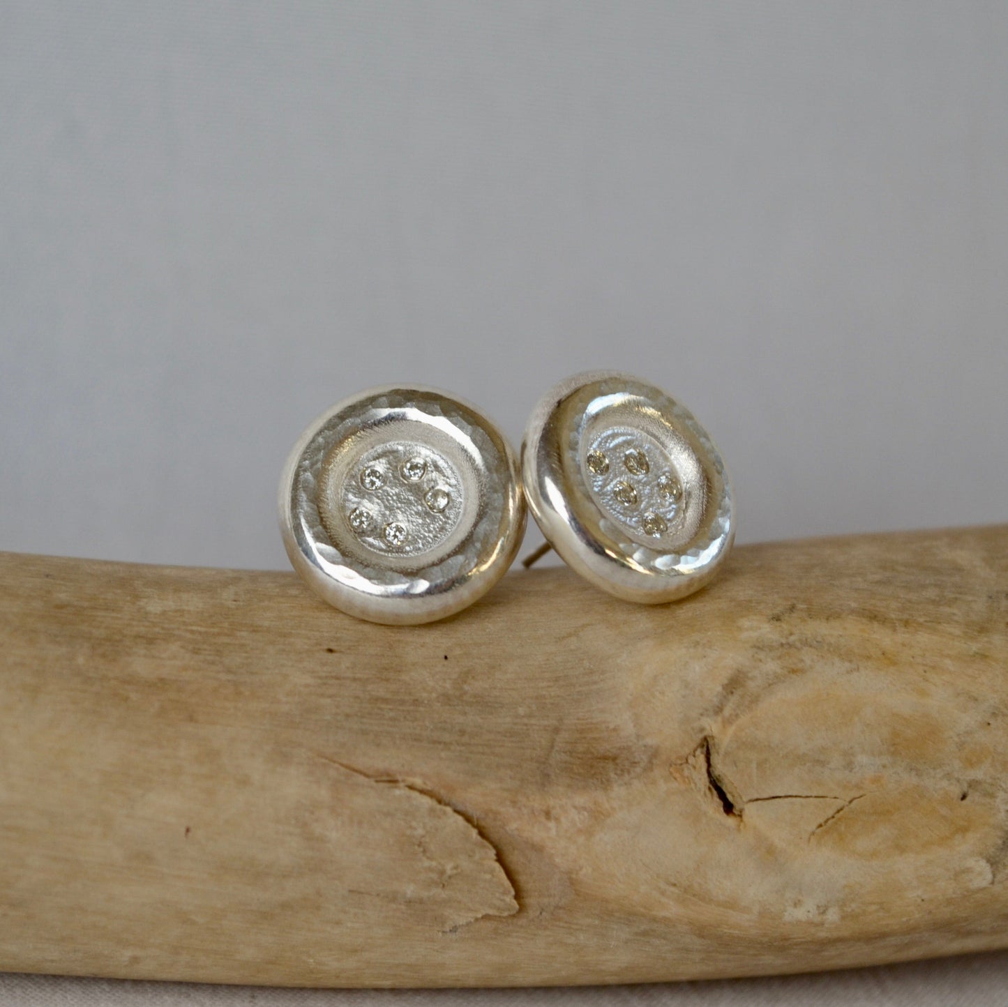 Silver round earrings on a wooden surface with a gray background