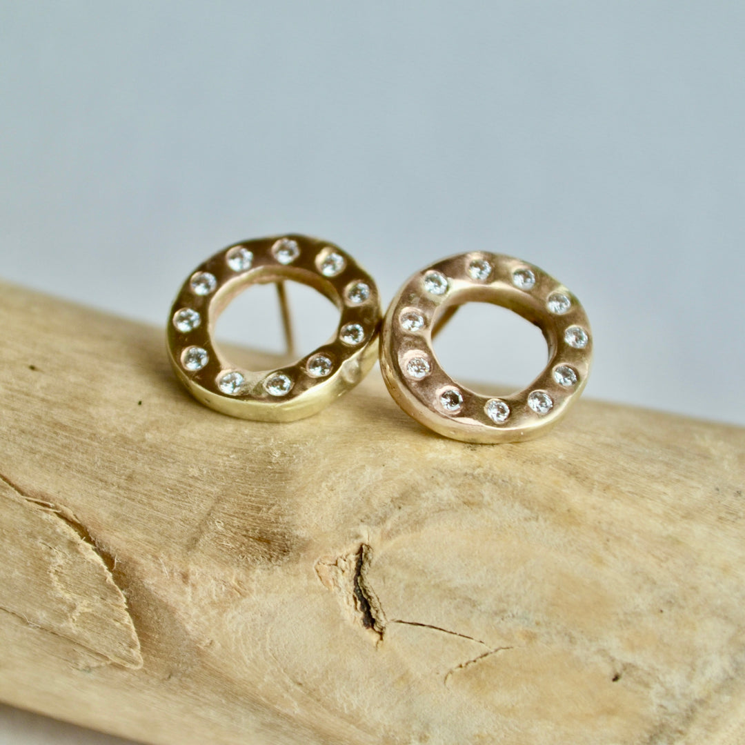Gold earrings with small diamonds on a wooden surface