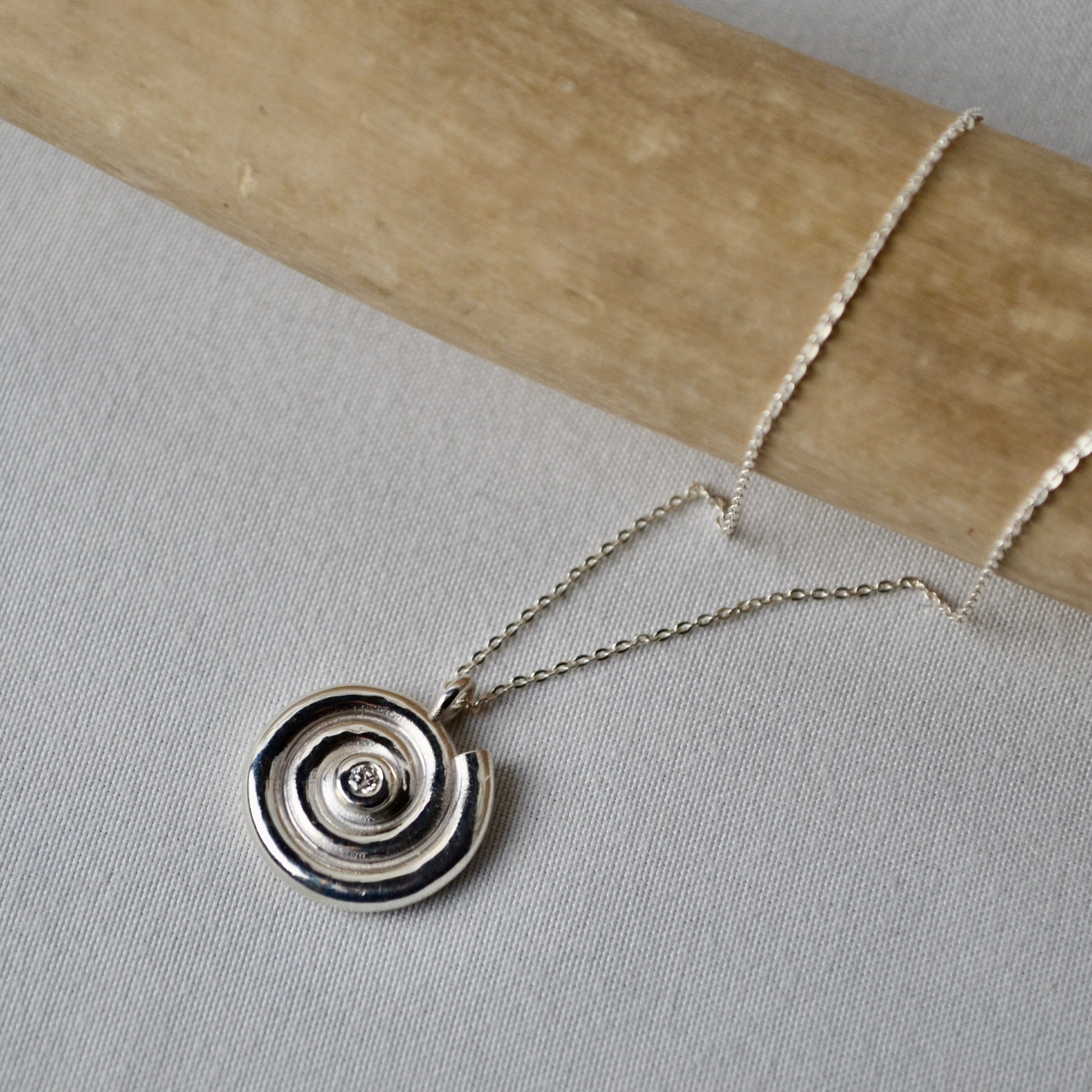 Silver necklace with a circular pendant on a light gray surface