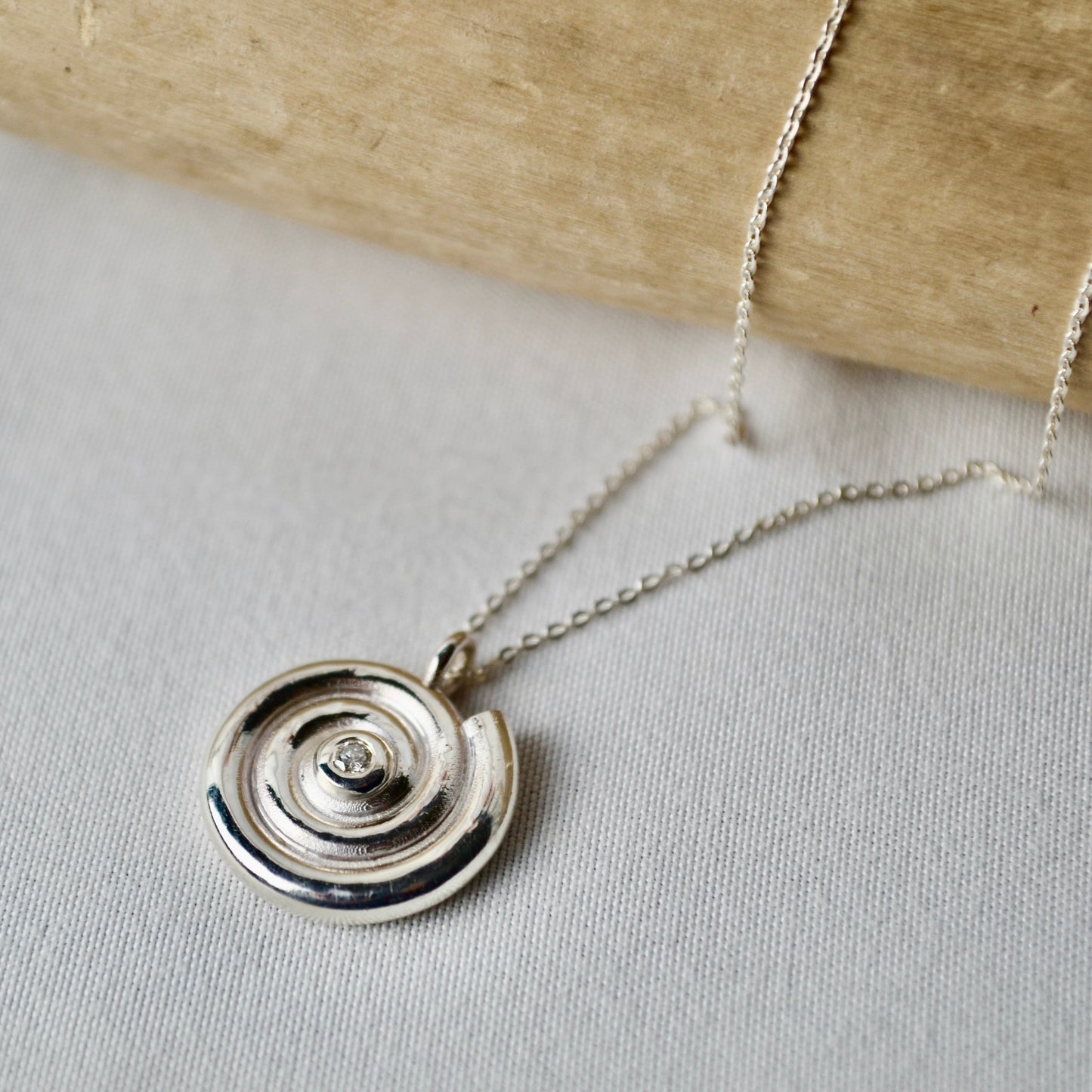 Silver necklace with a circular pendant on a light gray surface