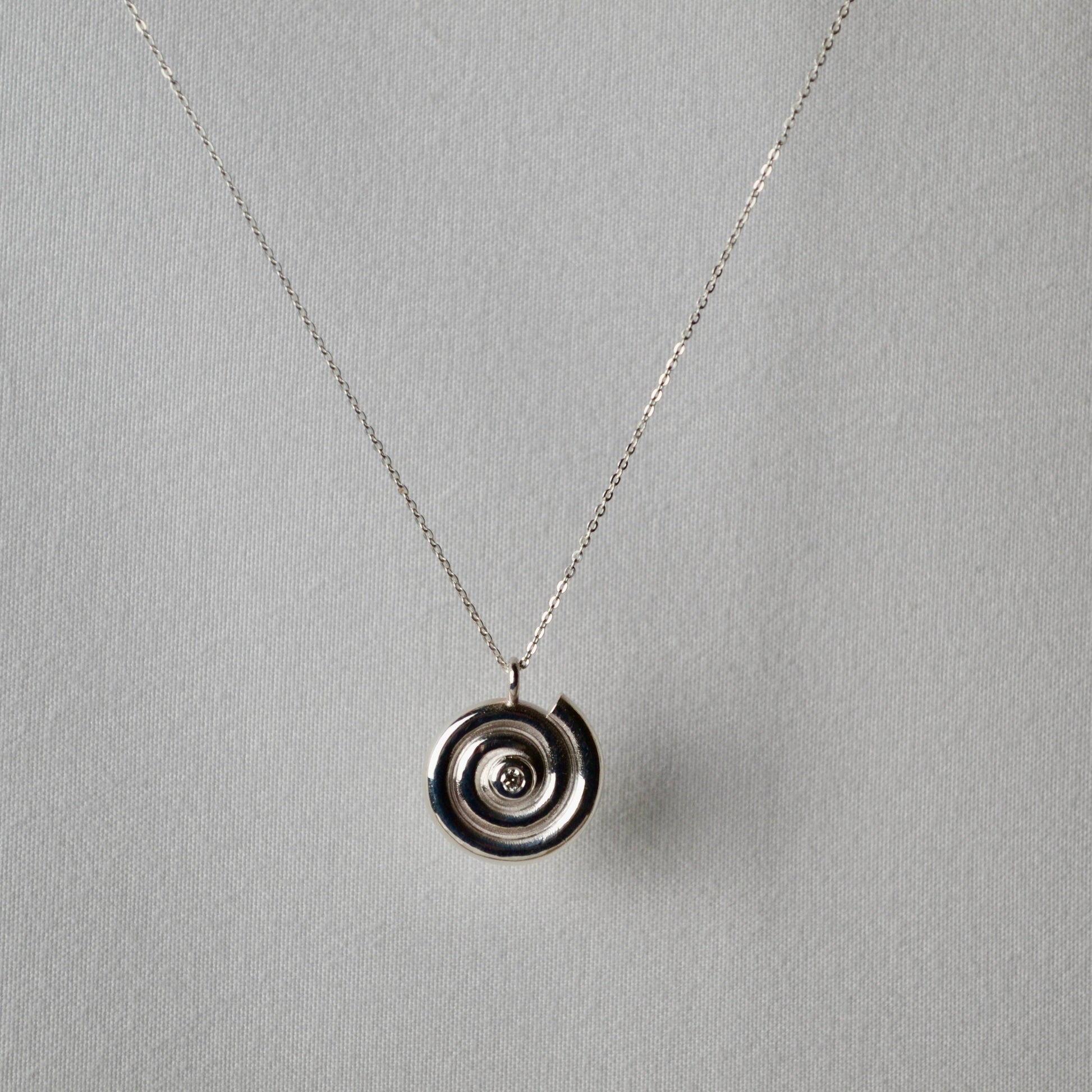 Silver necklace with a circular pendant on a gray background