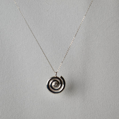 Silver necklace with a circular pendant on a gray background