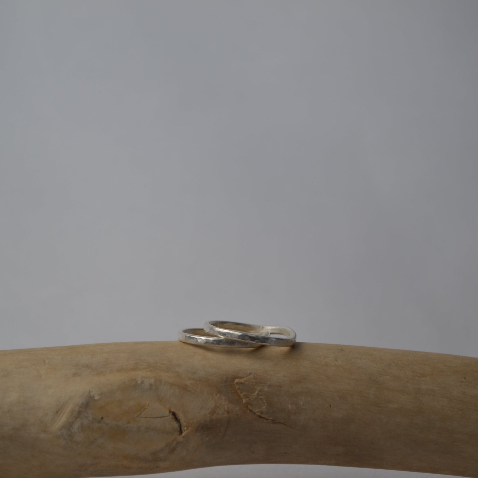 Silver ring on a wooden branch with a plain background