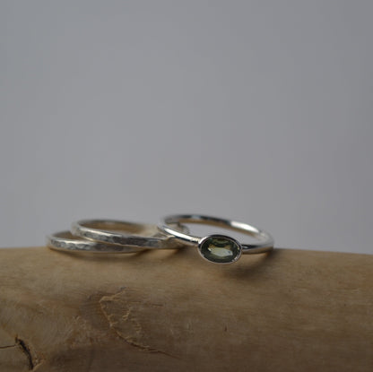 Silver ring with green stone on a textured surface