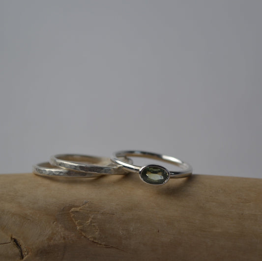 Silver ring with green stone on a textured surface