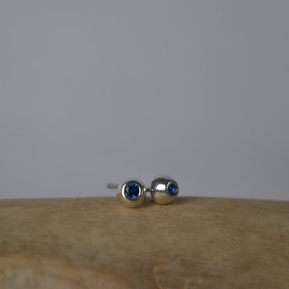 Pair of silver earrings with blue gemstones on a wooden surface.