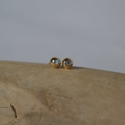 Gold earrings with gemstones on a wooden surface