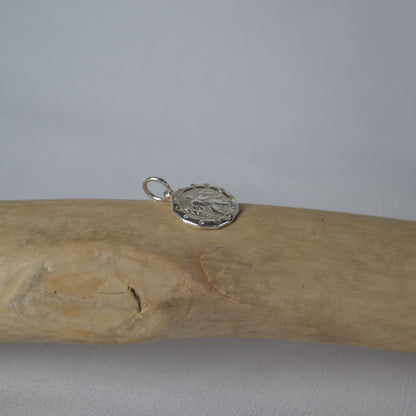 Wooden stick with a silver pendant on a gray background