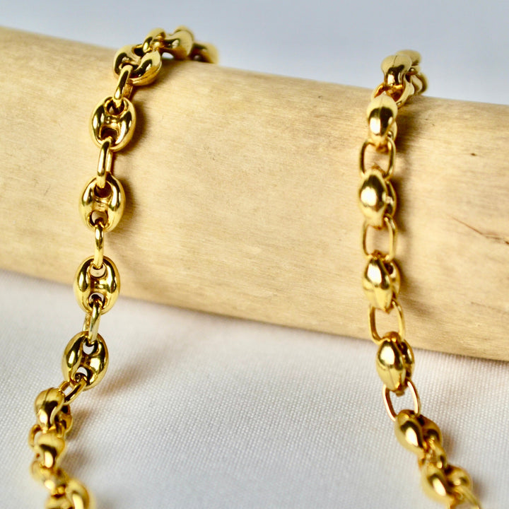 Gold chain bracelet on a wooden stick with a light background