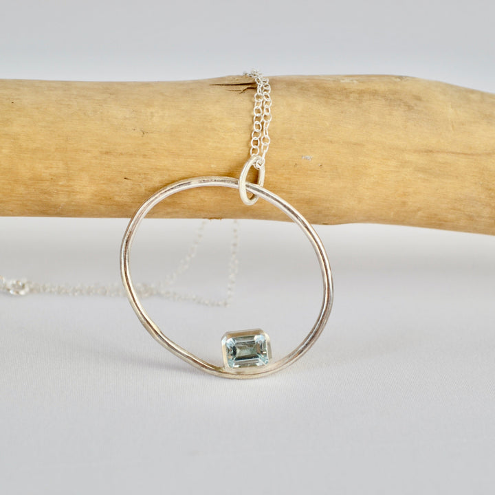 Silver ring with a green gemstone on a white background