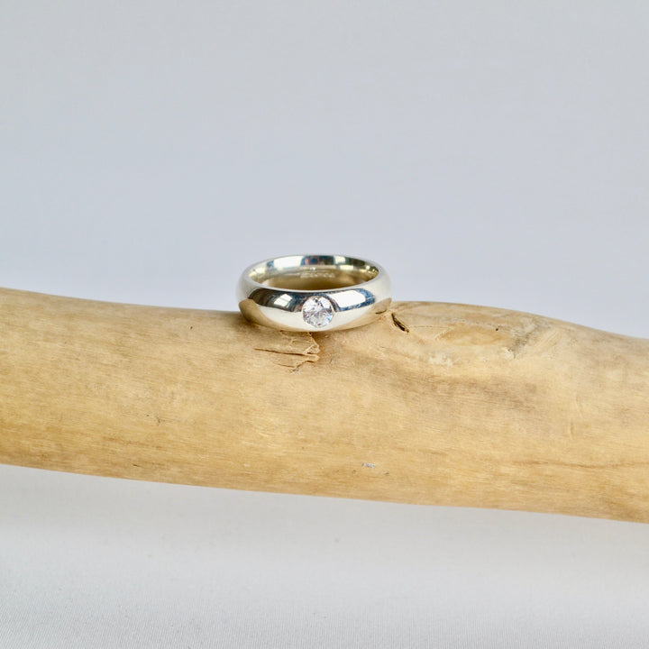 Silver ring on a wooden stick with a neutral background