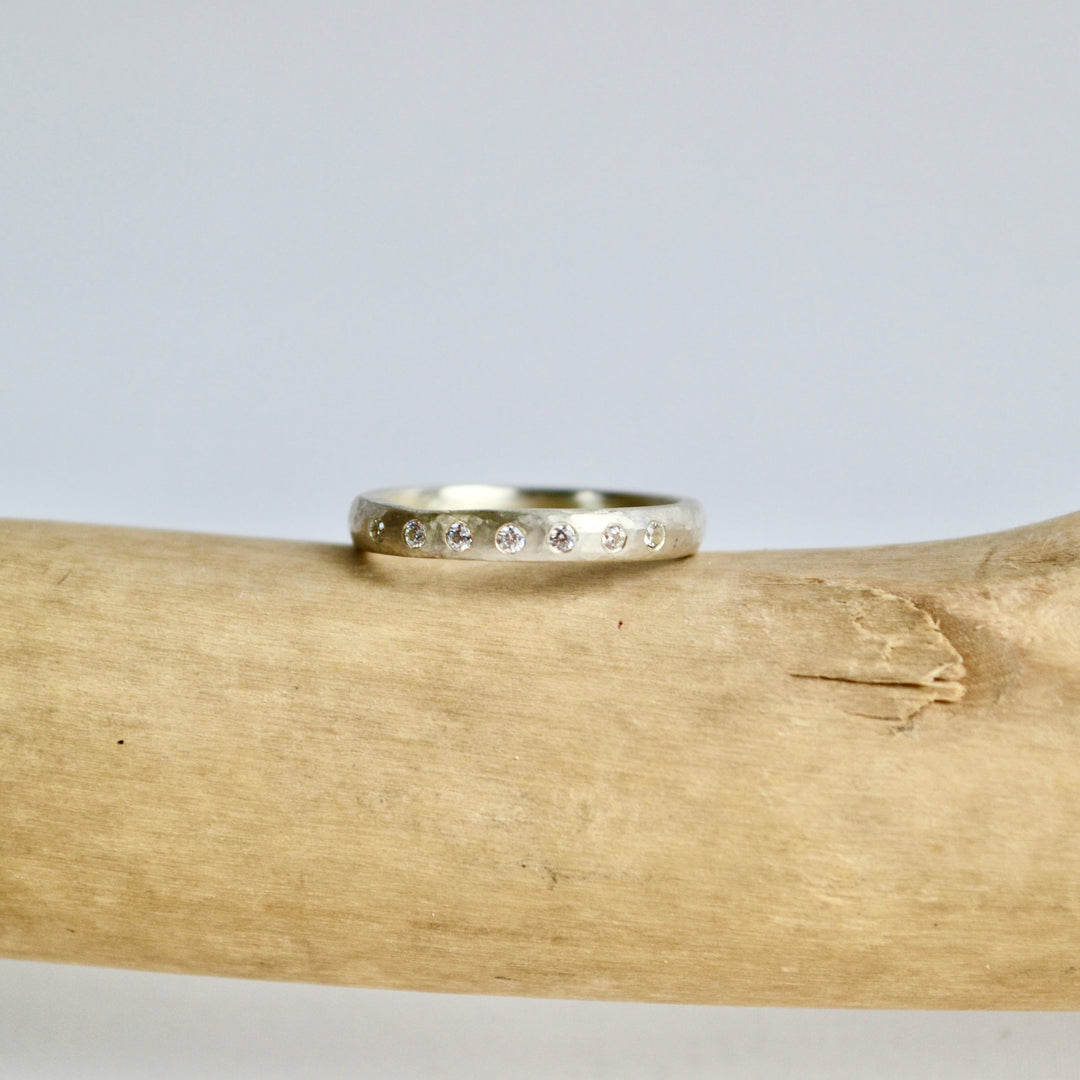 Silver ring with engraved text on a wooden log against a gray background