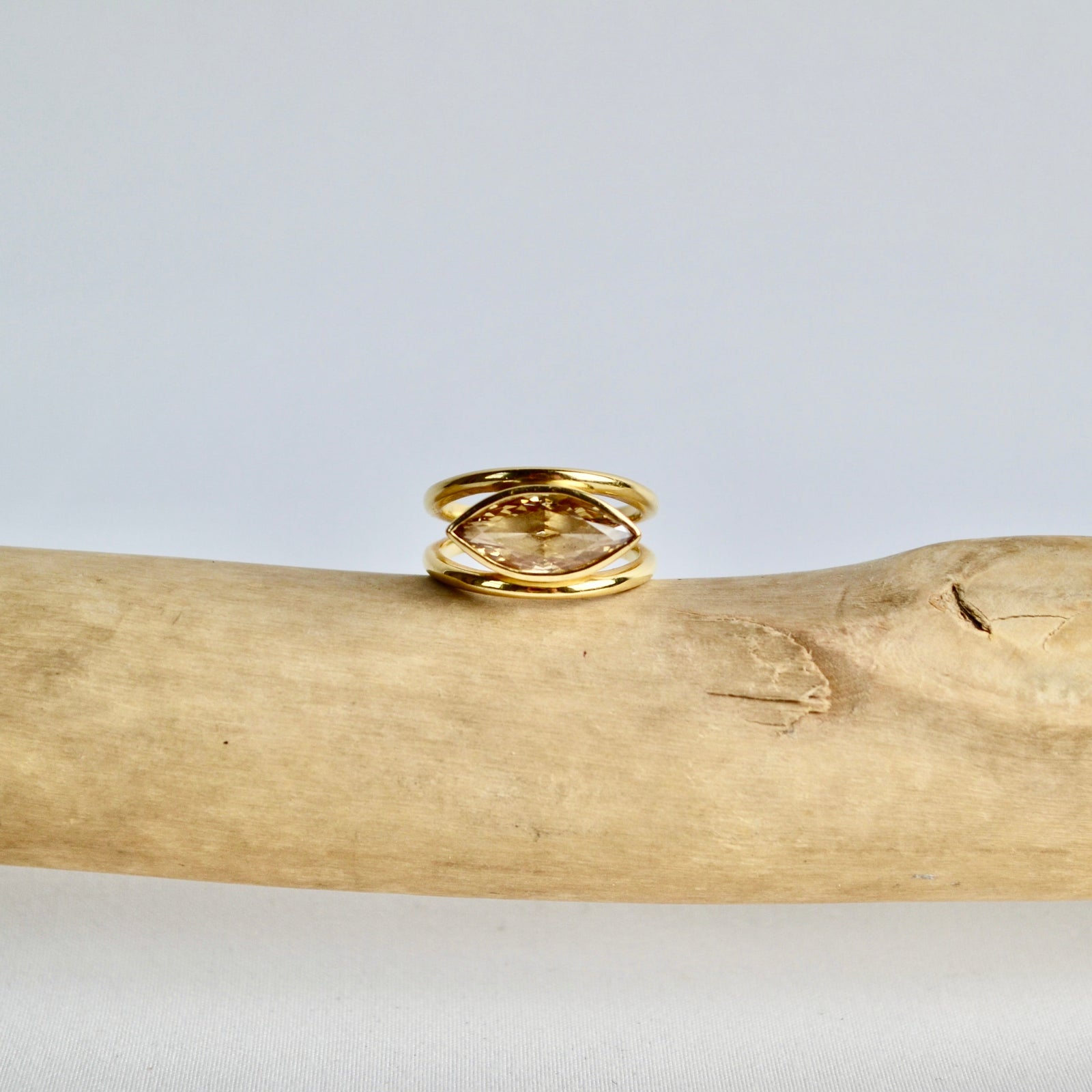 Gold ring on a wooden branch with a light gray background