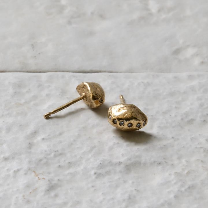 diamond gold studs pictured on white brick in the Cotswold&