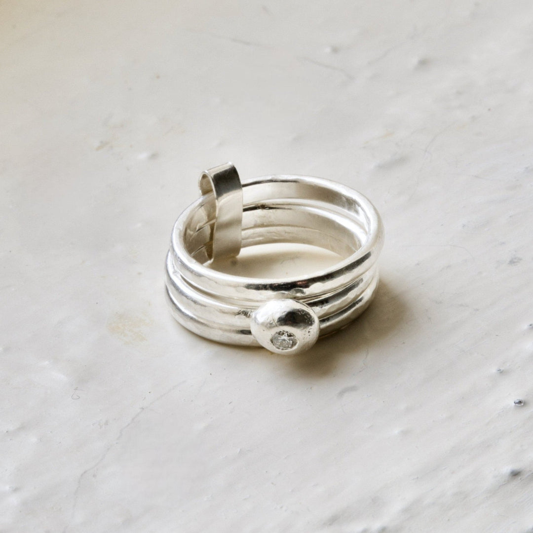 A sterling silver ring with a central white diamond on a textured surface.