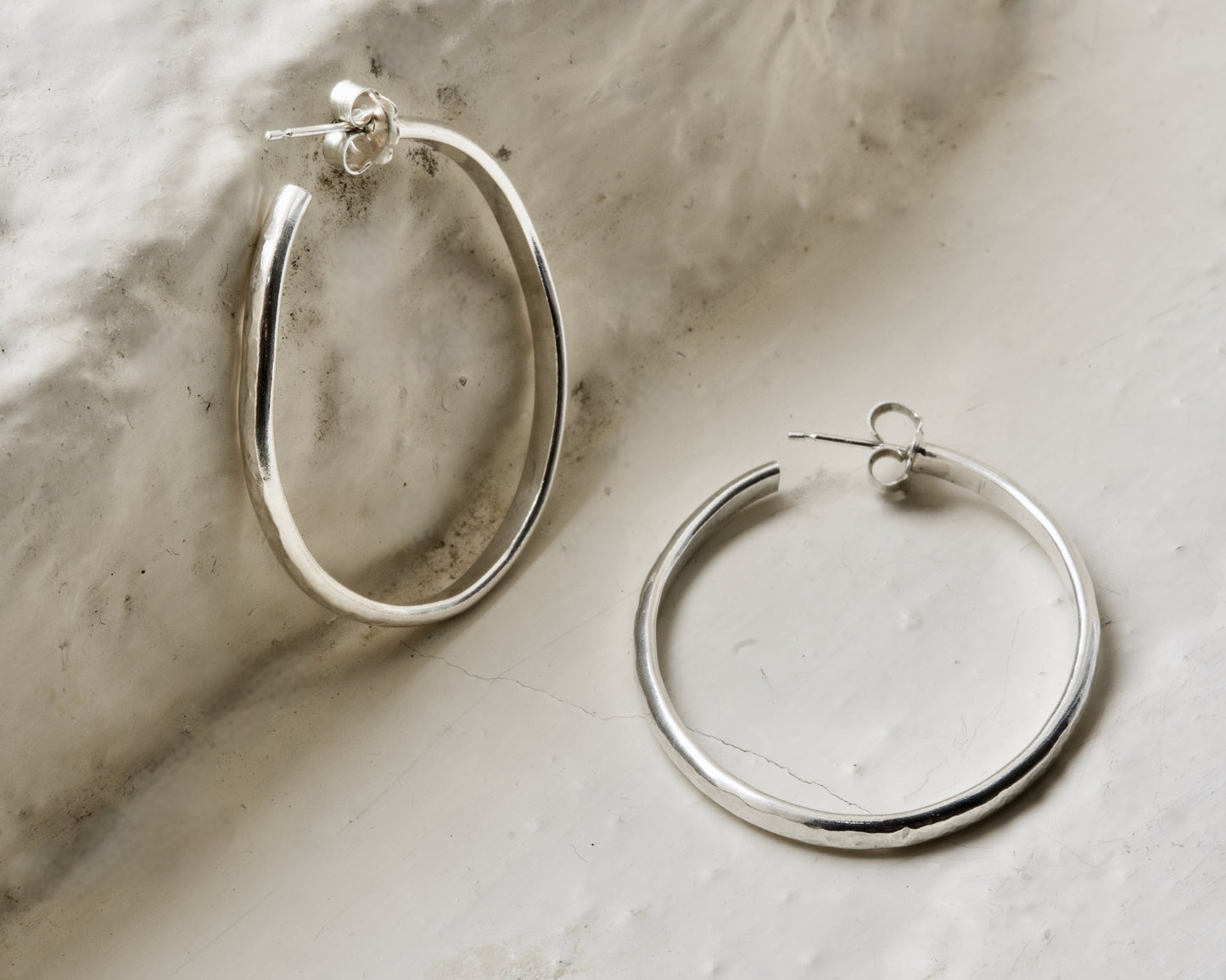 Classic pair of sterling silver hoops, photographed on white brick in the Cotswolds.