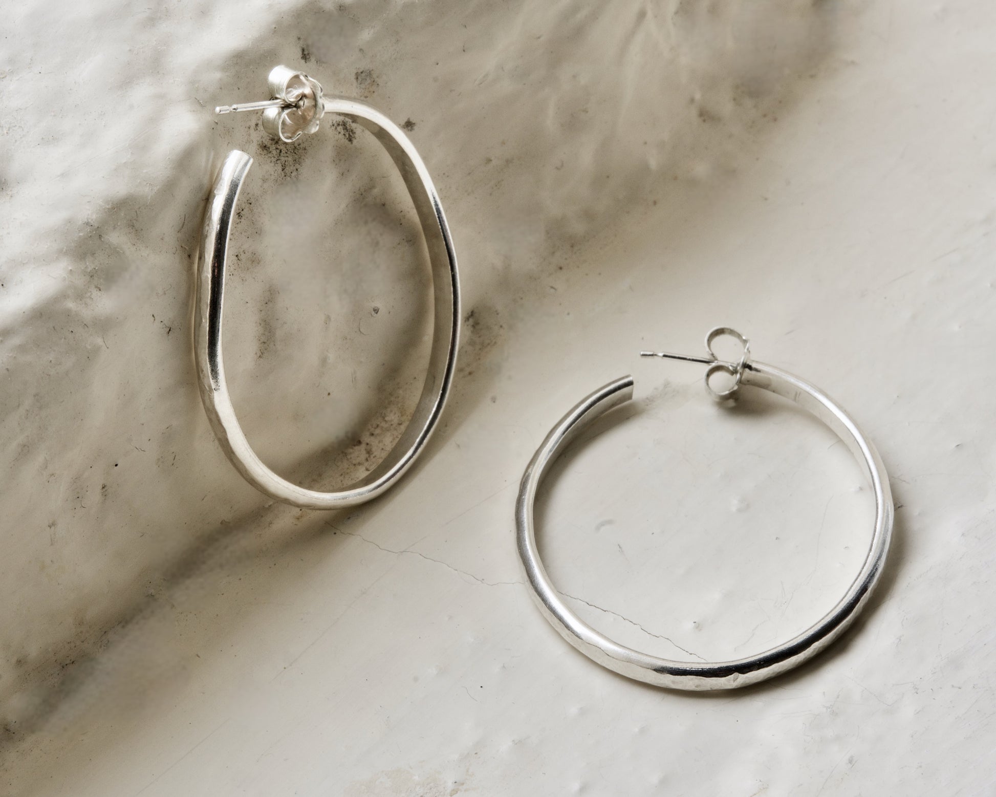 Classic pair of sterling silver hoops, photographed on white brick in the Cotswolds.