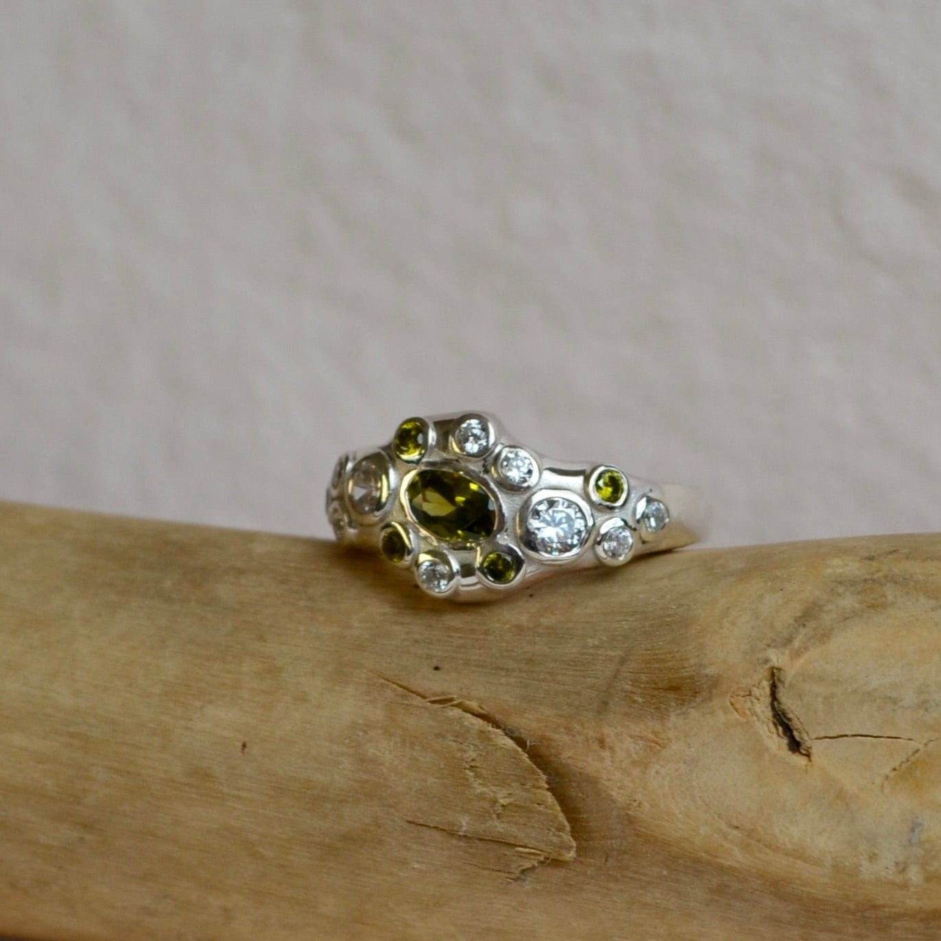 Silver ring with green gemstone on a wooden stick with twine