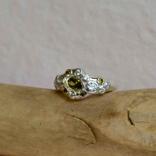 Silver ring with green gemstone on a wooden stick with twine