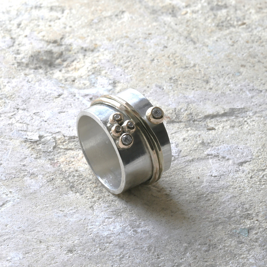 gold, diamond and silver spinning ring photographed on Cotswold stone. Handmade fine jewellery by Madeleine.