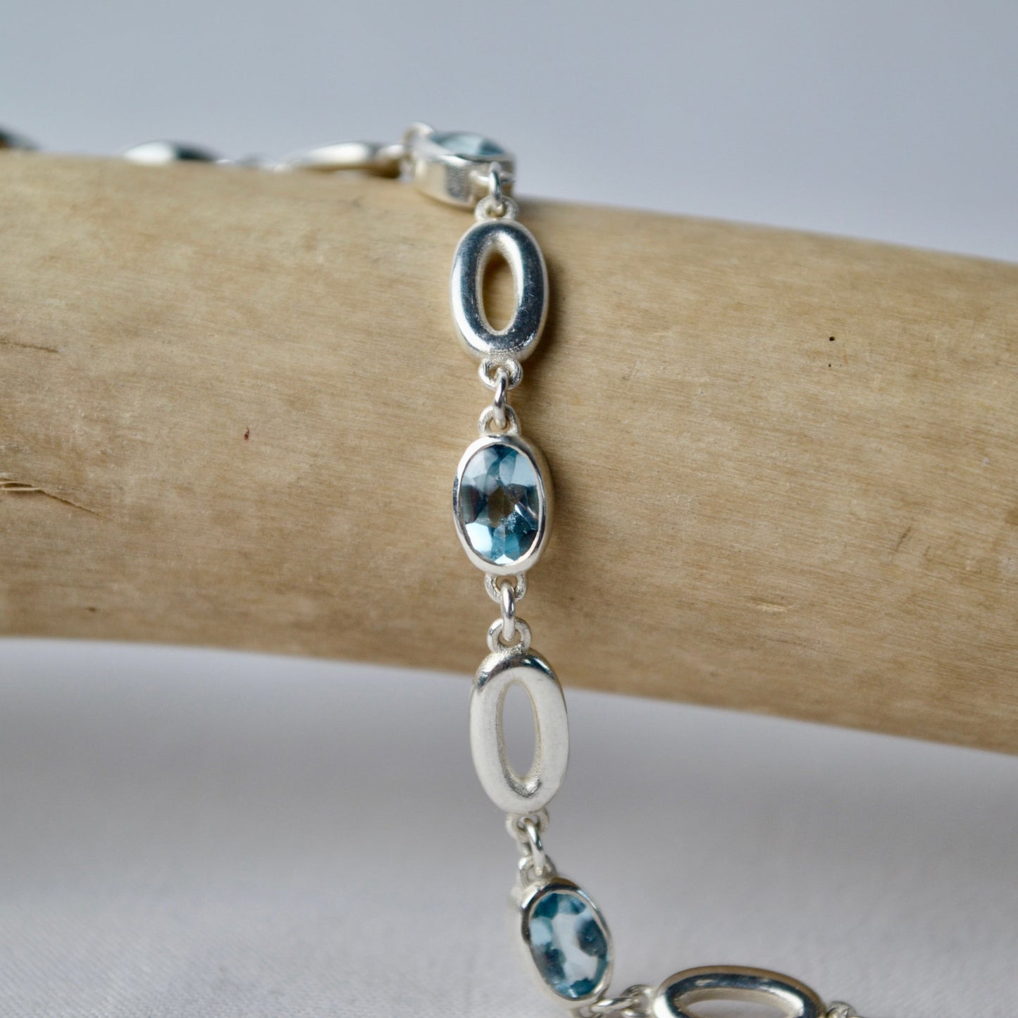 Silver bracelet with blue stones on a wooden branch
