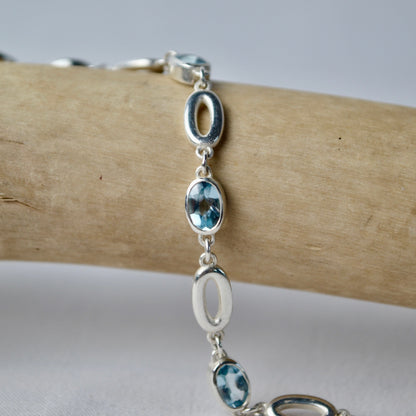 Silver bracelet with blue stones on a wooden branch