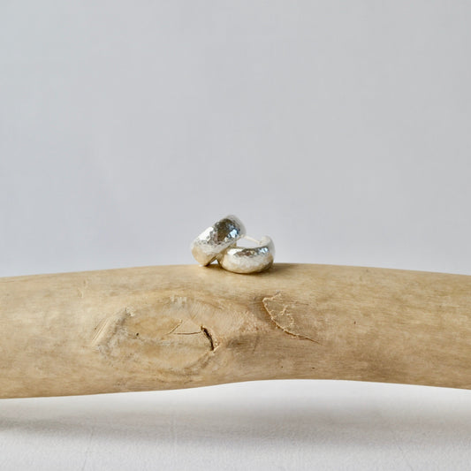 Two silver rings on a piece of driftwood with a plain background