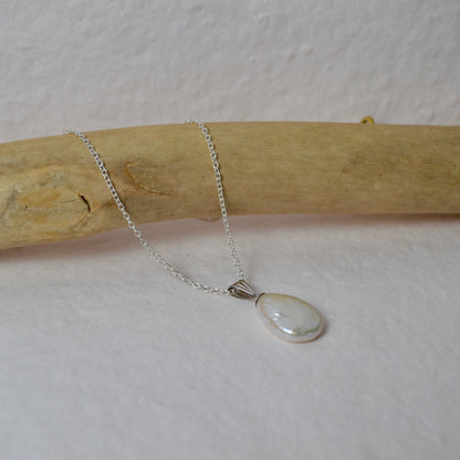 Necklace with a pendant on a wooden stick against a light background