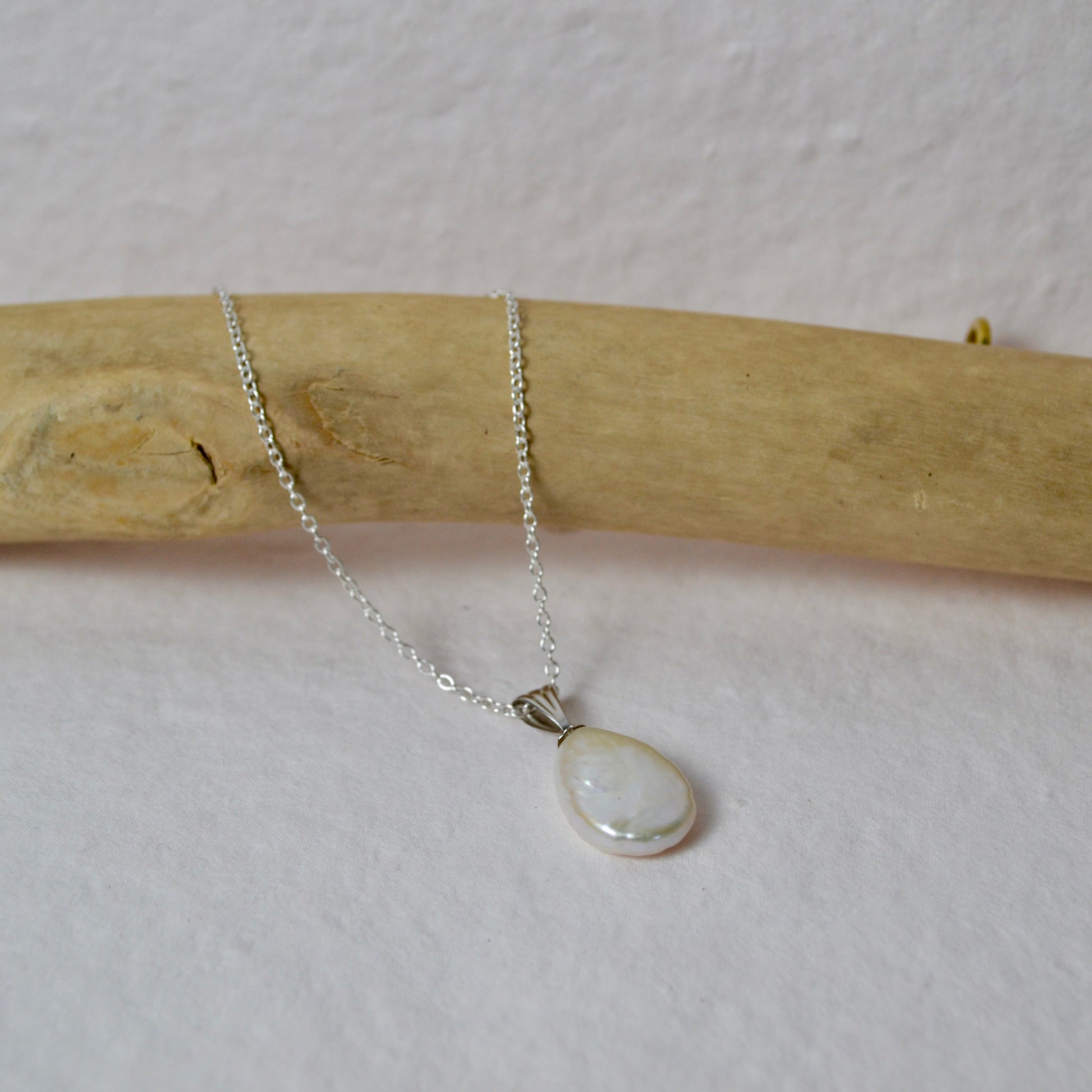 Silver necklace with a teardrop-shaped pendant on a white background
