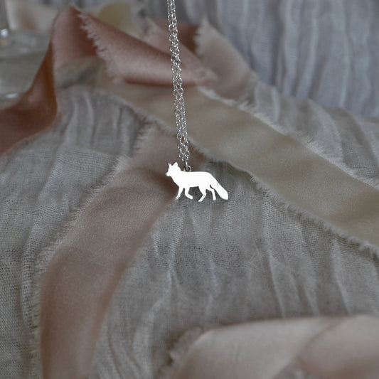 Silver necklace with a fox pendant on a textured fabric background