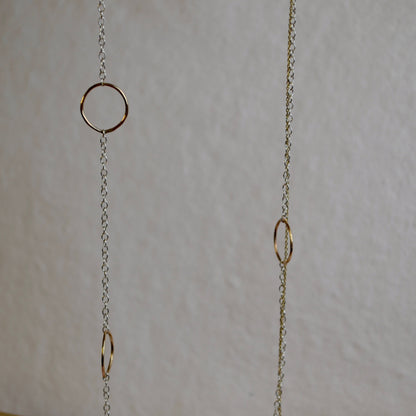 Gold chain with circular links on a light gray background