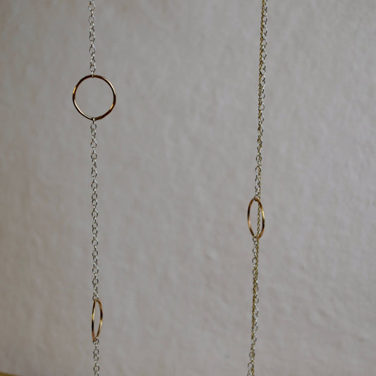 Gold chain with circular links on a light gray background