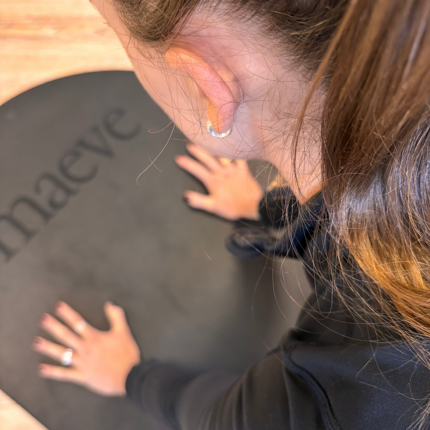 Person wearing a blue jacket with 'maeve' branding on a black surface.